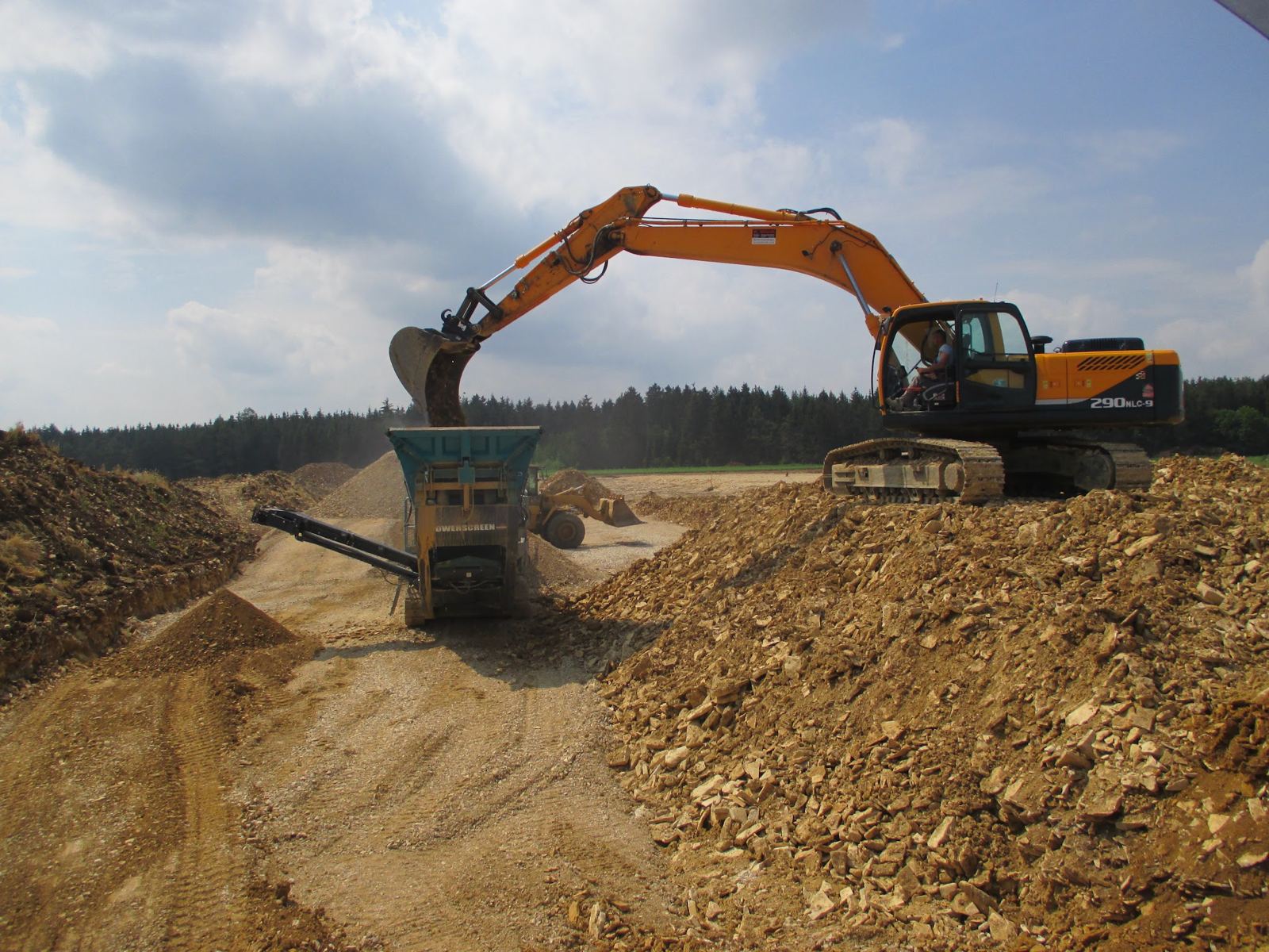 Bagger und mobile Brechanlage beim Aufbereiten von Bruchgestein